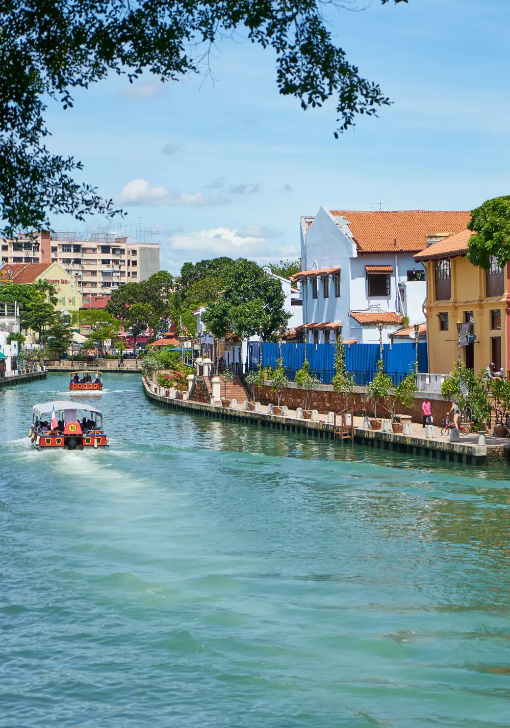 A river boat on the Melaka River, with colourful heritage buildings along the bank