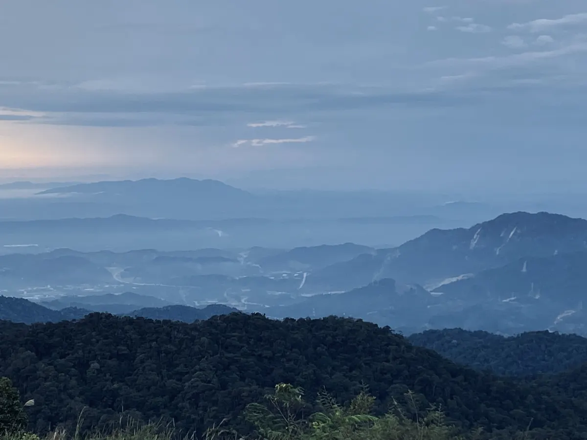 Layers of forested hills in the Bentong district fading into blue haze and low cloud, seen from Genting Highlands at dusk
