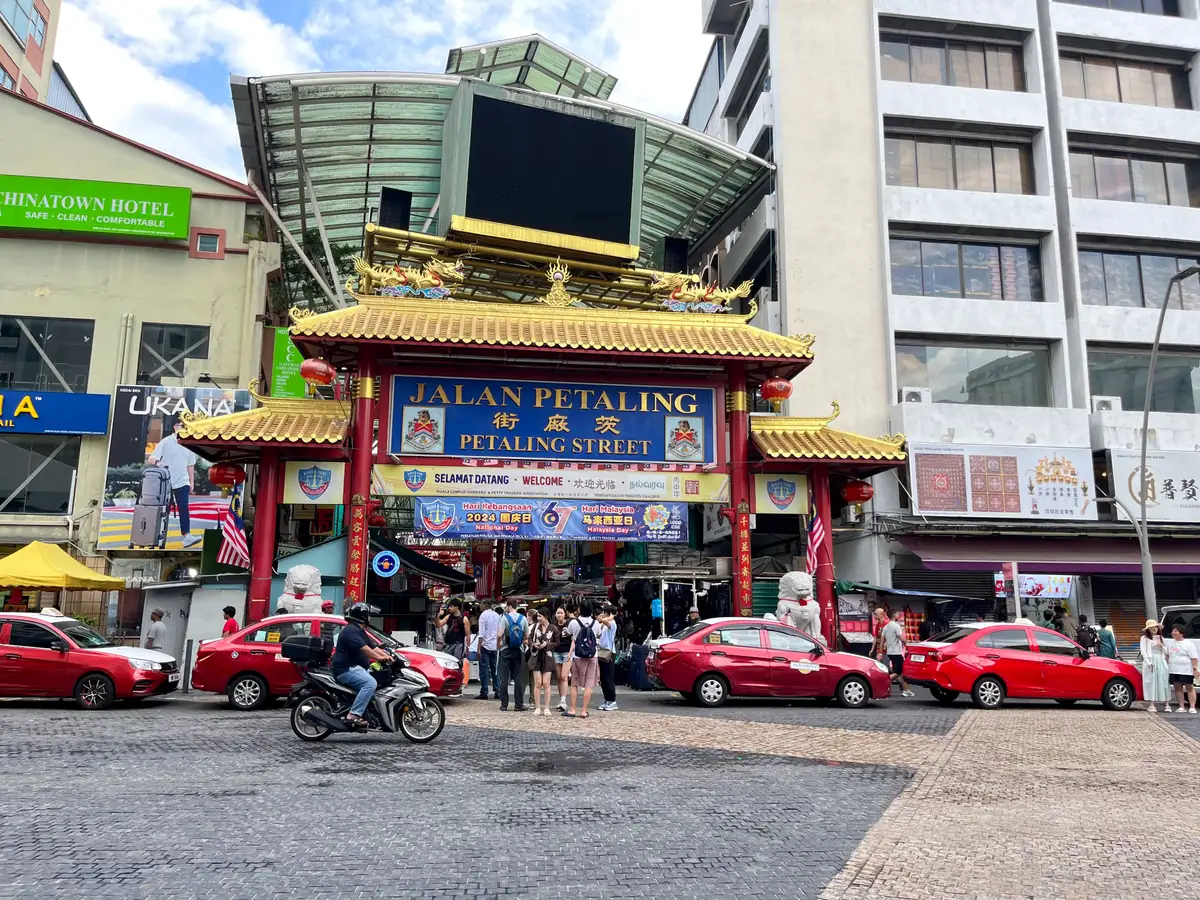 The ornate red and gold gateway to Jalan Petaling, Kuala Lumpur’s Chinatown market street, with taxis and visitors in front