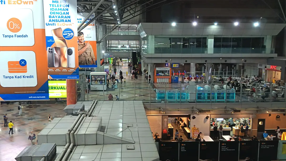The busy concourse at KL Sentral station in Kuala Lumpur, with ticket counters, food outlets and travelers under a high roof
