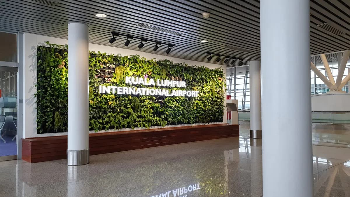 A living green wall inside the terminal with the words Kuala Lumpur International Airport in white letters