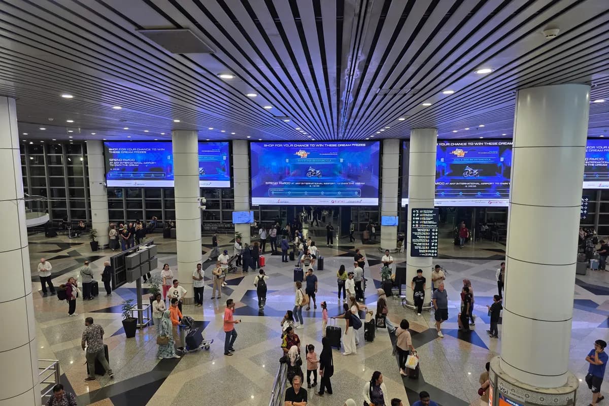 Travellers with luggage crossing the arrival hall of Kuala Lumpur International Airport Terminal 1, seen from the level above