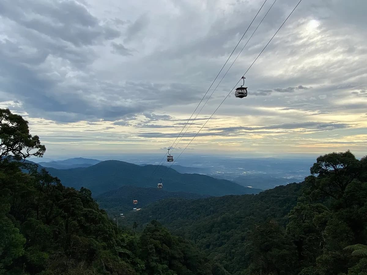 A Genting cable car gondola travelling above dense green rainforest on the mountain slope