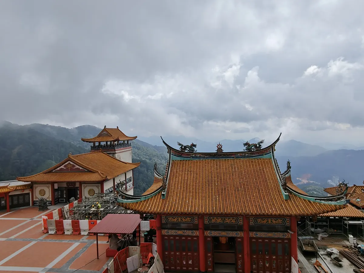 Red-and-gold tiled roofs of Chin Swee Caves Temple in Genting Highlands, with cloud over the surrounding mountains