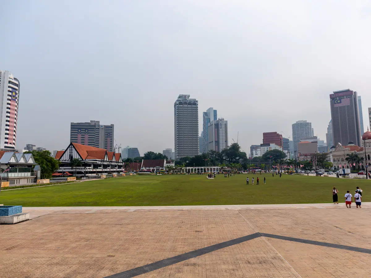 Dataran Merdeka in Kuala Lumpur: a wide green lawn with the Royal Selangor Club on the left, the Sultan Abdul Samad Building on the right and modern towers behind