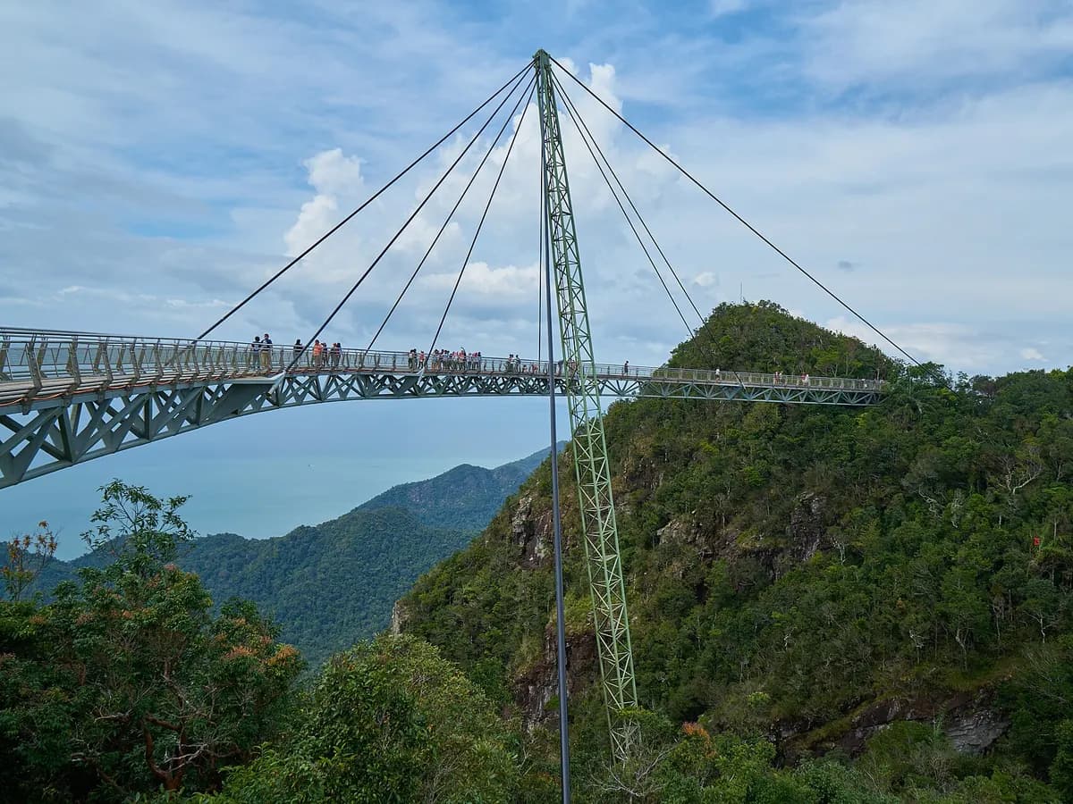The curved Langkawi Sky Bridge on a forested mountain peak, with the sea and hills beyond