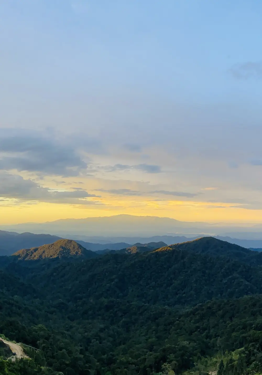 Forested ridges rolling away under a sunset sky, seen from a viewpoint in the Genting Highlands, with layers of hills fading into the haze